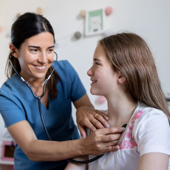 Eine Kinderärztin untersucht eine Jugendliche mit einem Steth