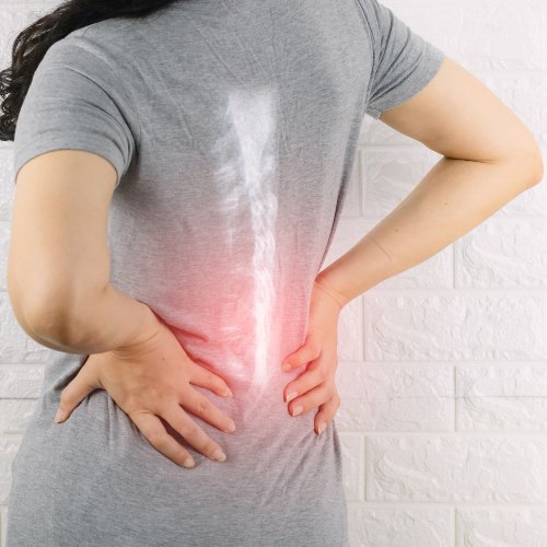 Eine Frau hält sich den Rücken und ein Fokus liegt auf ihrer Wirbelsäule