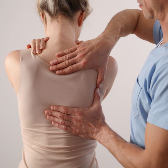 Ein Physiotherapeut massiert einer Frau den Rücken.